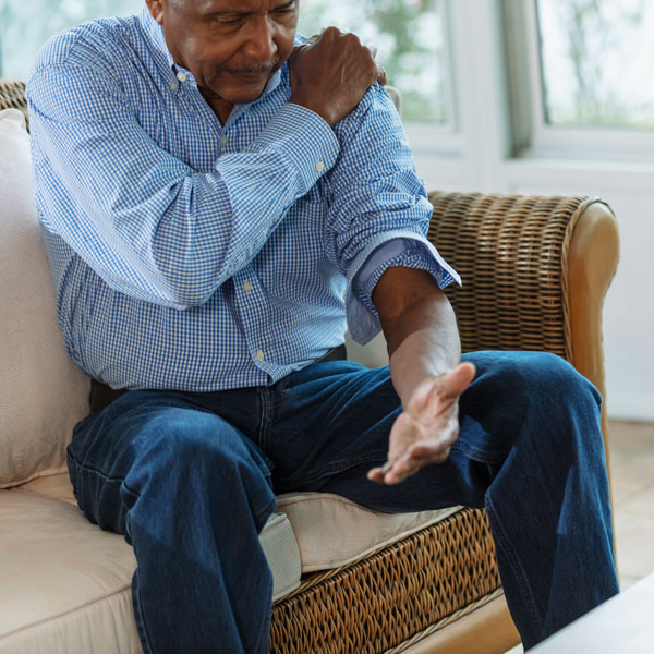 mature man sitting on couch and pressing shoulder