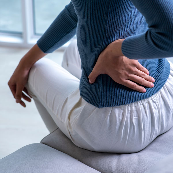 woman sitting on couch feeling hip pain