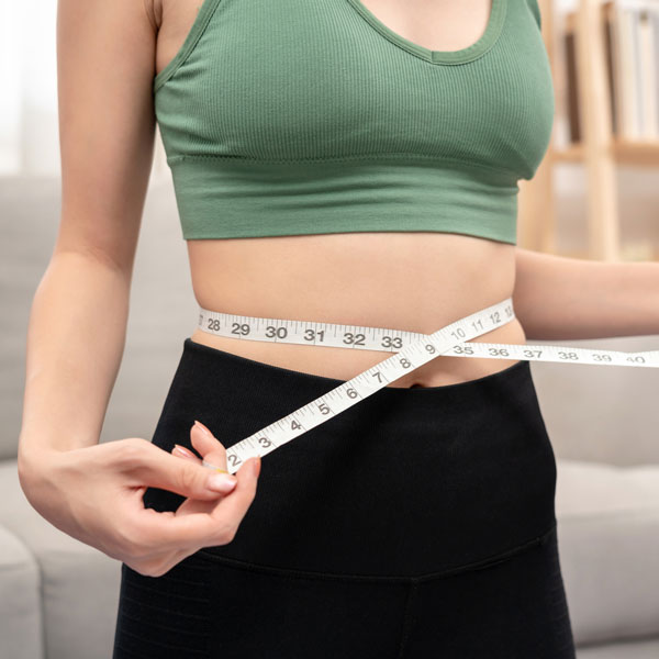 Woman holding measuring tape around waist